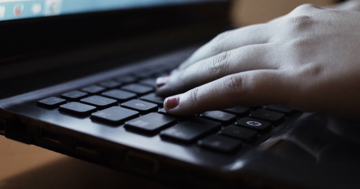 Hands typing on a laptop keyboard, the everyday interface of machine translation tools